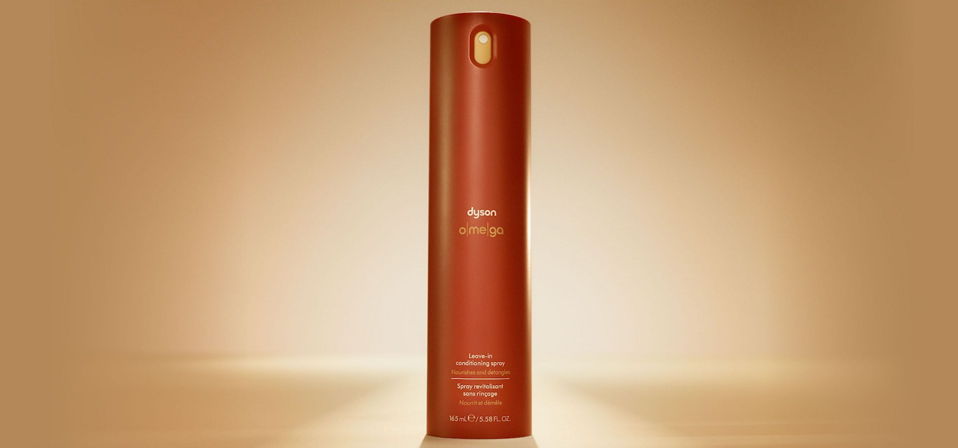 Dyson Omega leave-in conditioning spray illuminated with a warm orange glow.