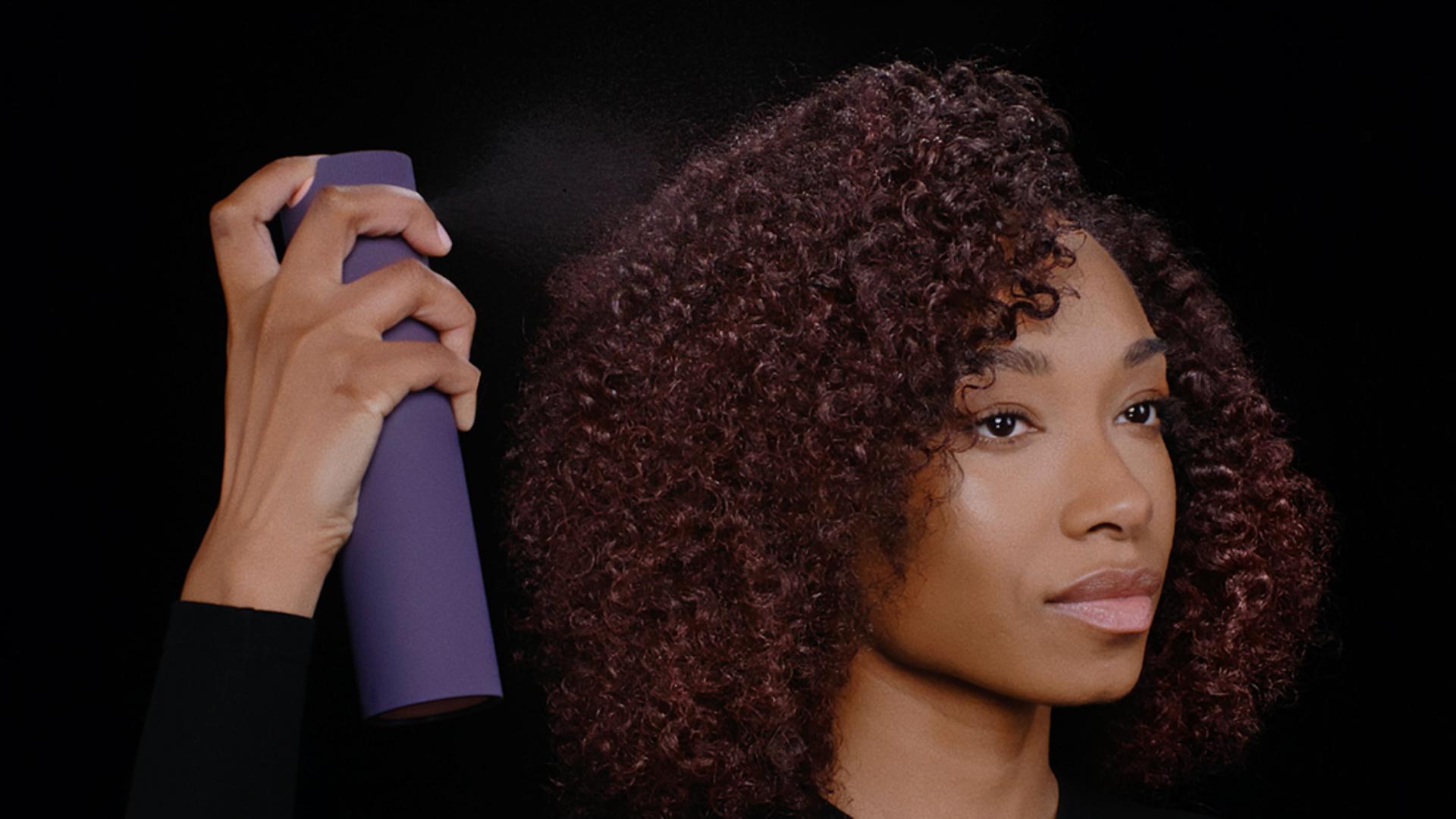 Model applies Dyson Chitosan Multi-use styling spray to her styled hair.