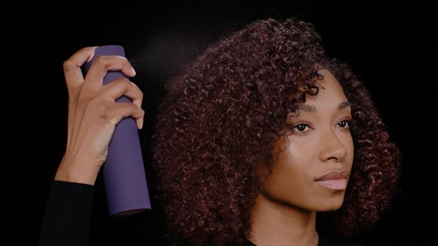 Model applies Dyson Chitosan Multi-use styling spray to her styled hair.