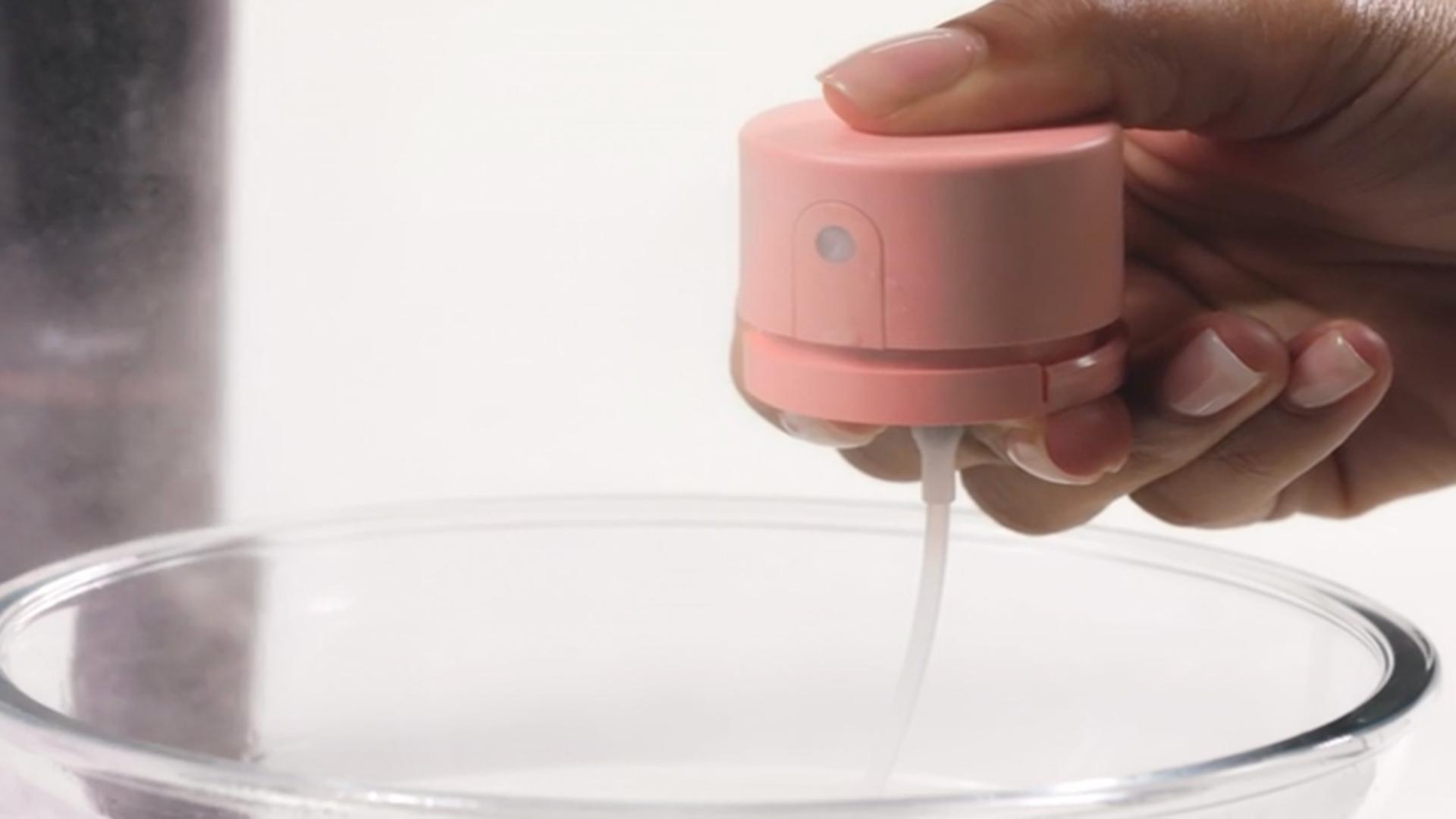 The pump of the Dyson Chitosan Multi-use styling spray is cleaned with clean water in a bowl.