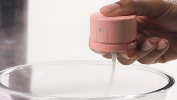 The pump of the Dyson Chitosan Multi-use styling spray is cleaned with clean water in a bowl.