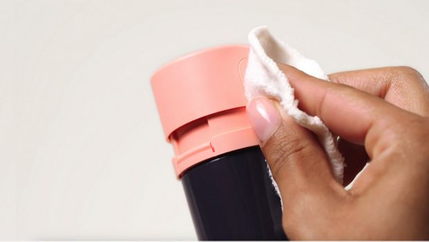 The pump of a Dyson Beauty bottle is cleaned with clean water in a bowl.