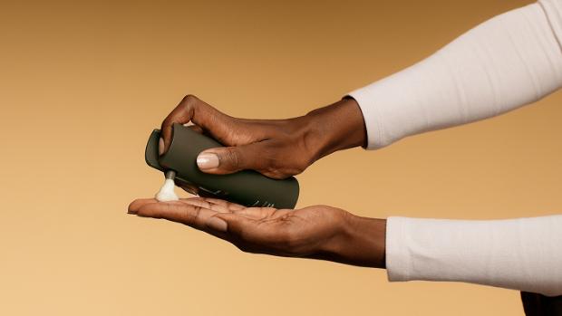 Model dispenses Dyson Amino Leave-in scalp bubble treatment into her hand.