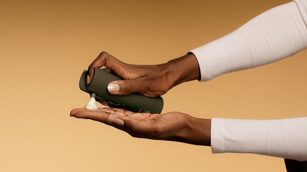 Model dispenses Dyson Amino Leave-in scalp bubble treatment into her hand.