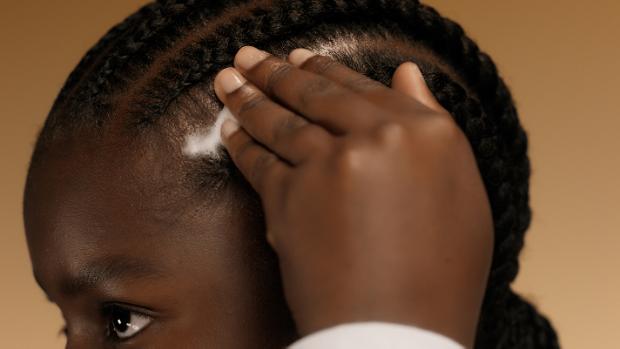 Model massages Dyson Amino Leave-in scalp bubble treatment into her scalp.