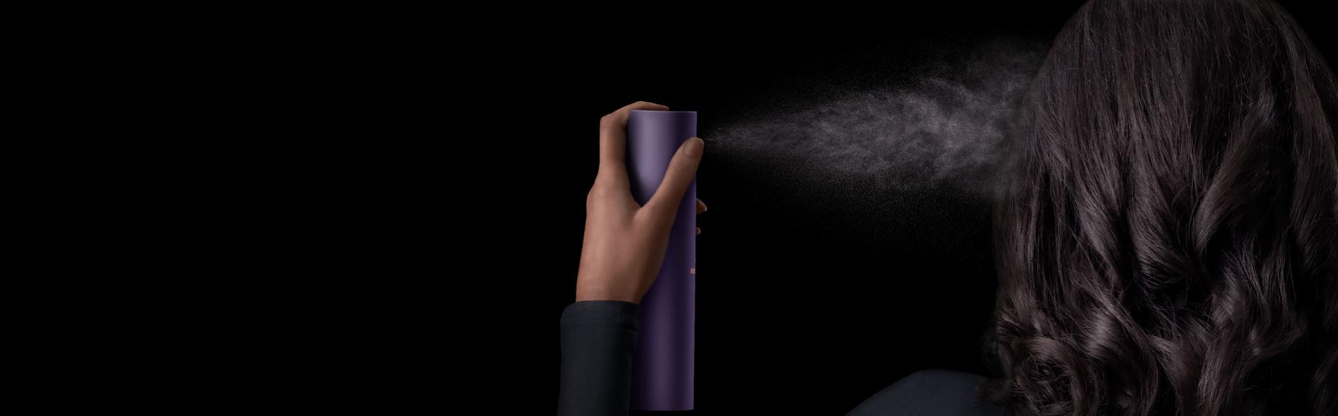 Model applies Dyson Chitosan Multi-use styling spray to her hair in a fine mist.