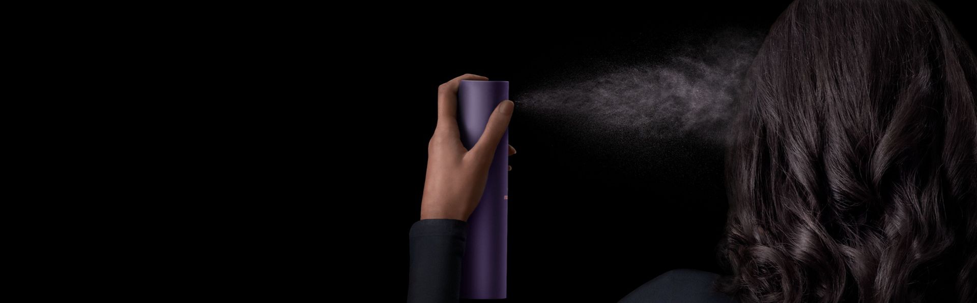 Model applies Dyson Chitosan Multi-use styling spray to her hair in a fine mist.