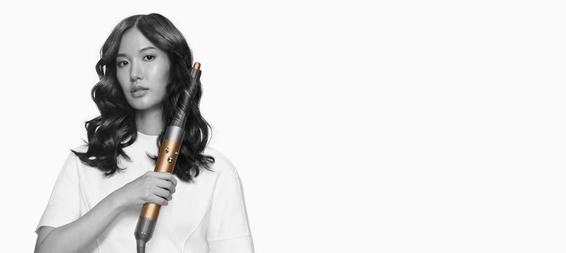 Woman using the Dyson Airwrap multi-styler to curl hair