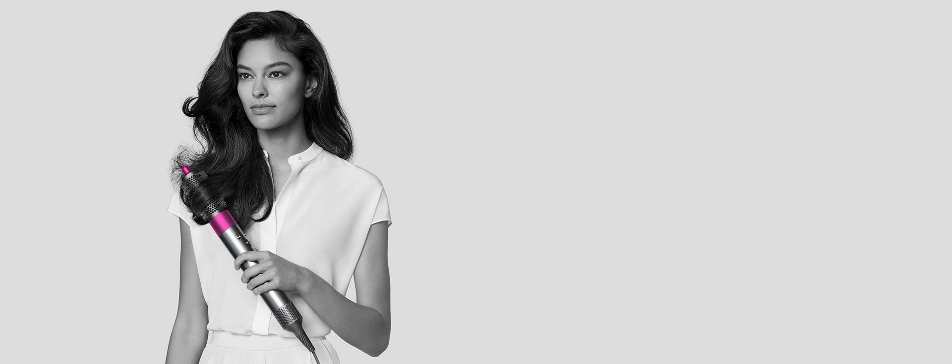 Woman styling her hair with the Dyson Airwrap Styler.