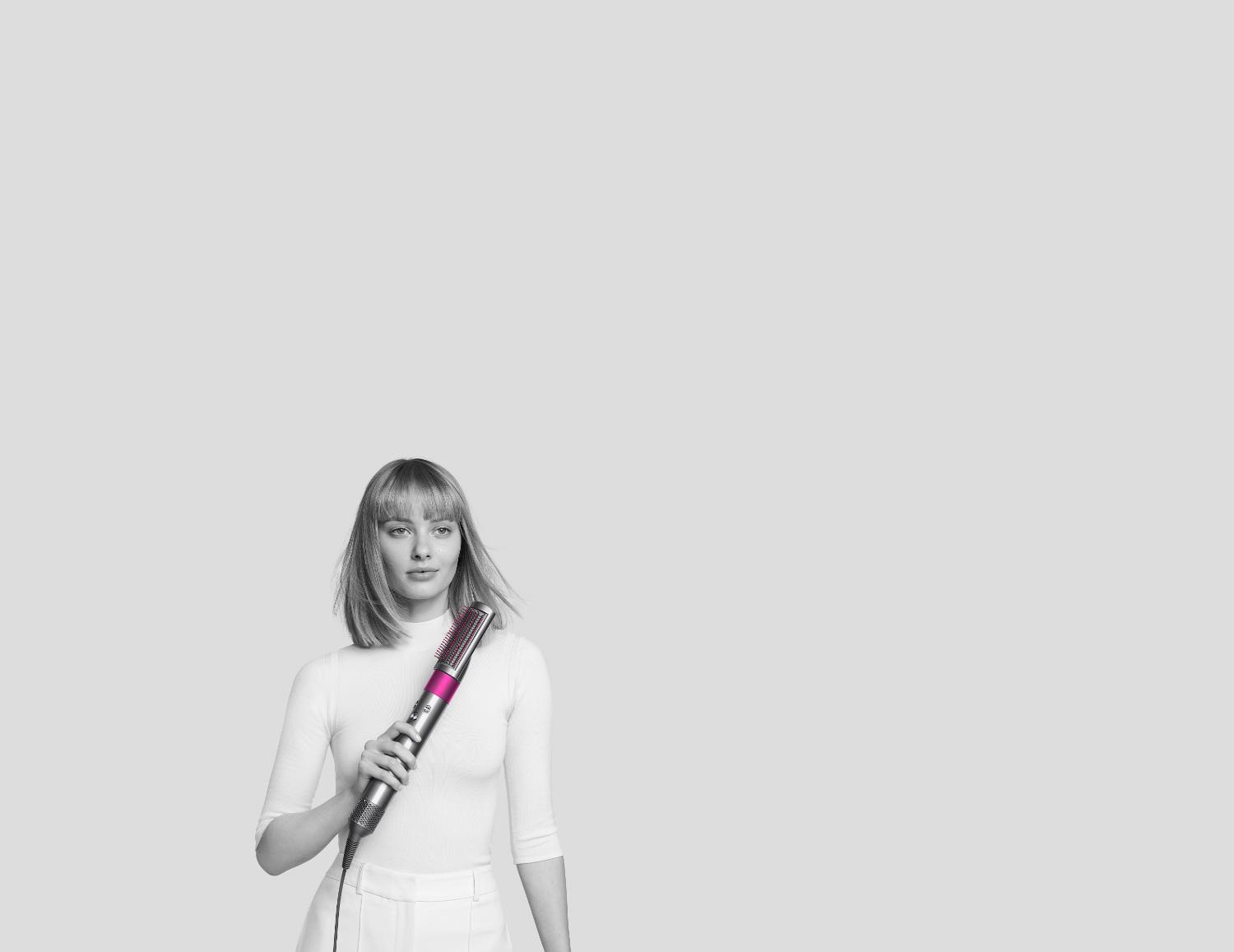 Woman styling hair with Dyson Airwrap styler.