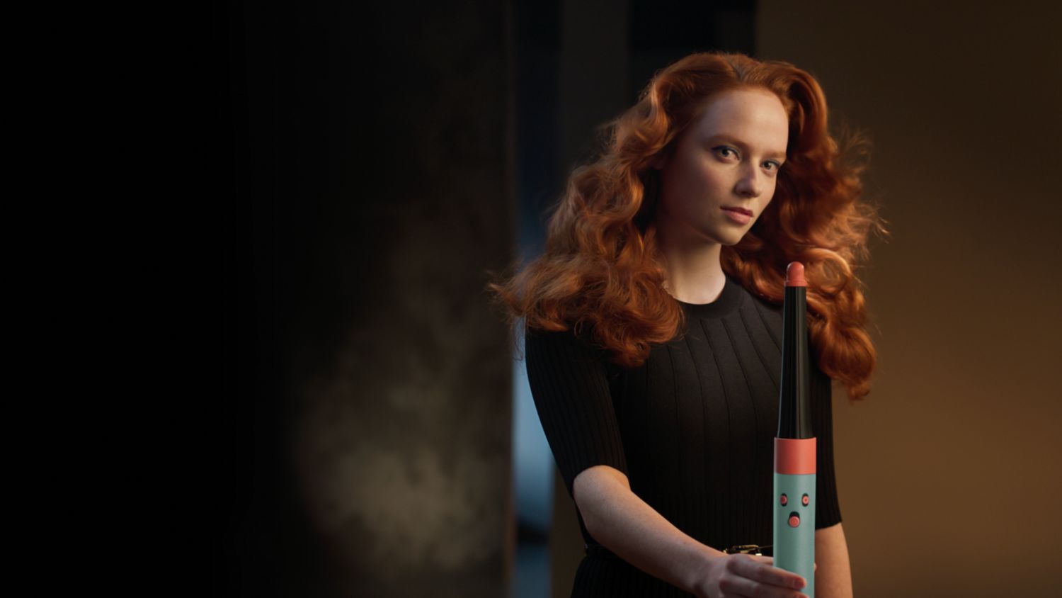 Frontalansicht einer Frau mit lockigem, gestyltem Haar, die den Dyson Airwrap ID hält.