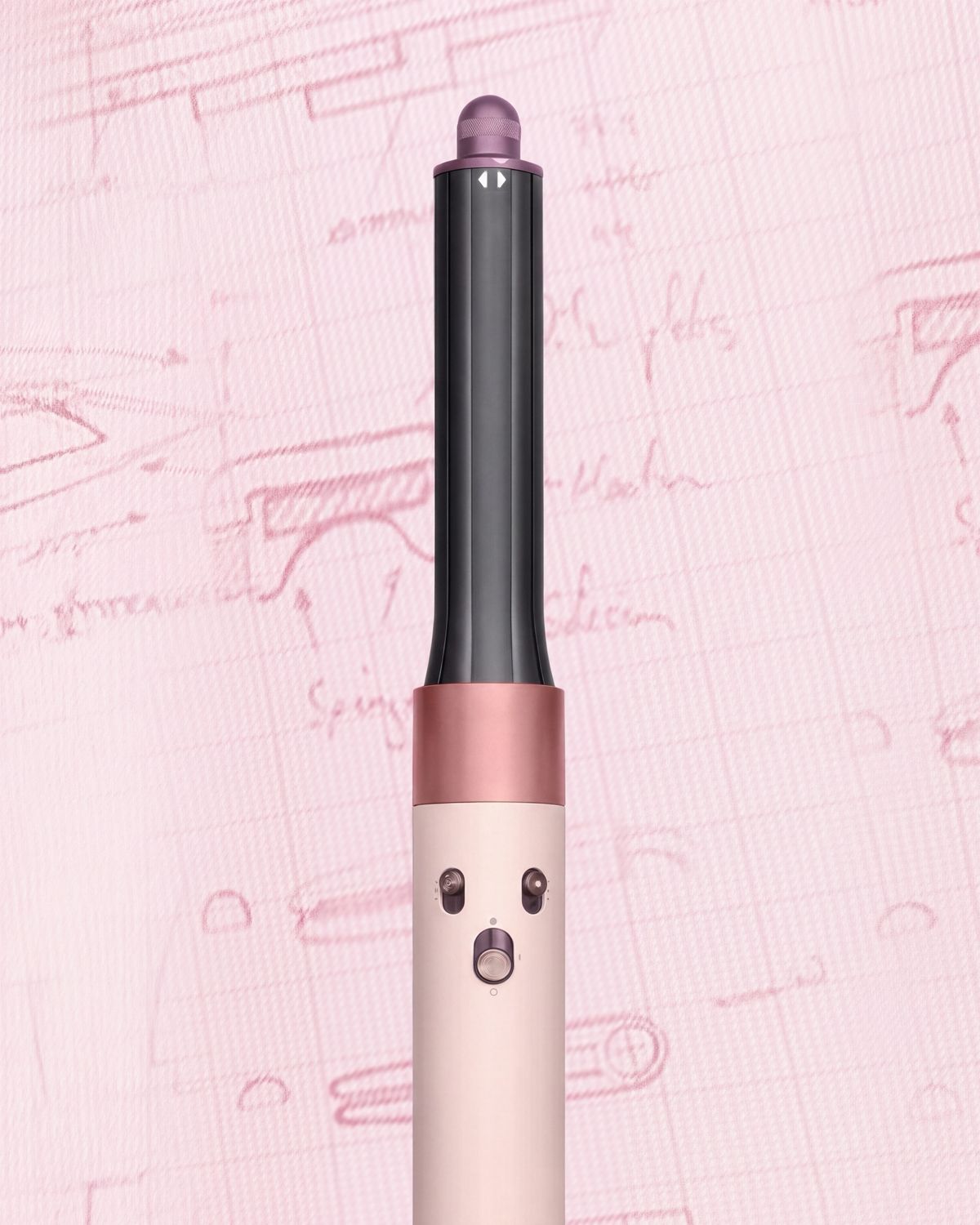 The Dyson Airwrap ID in front of pink engineering sketches.