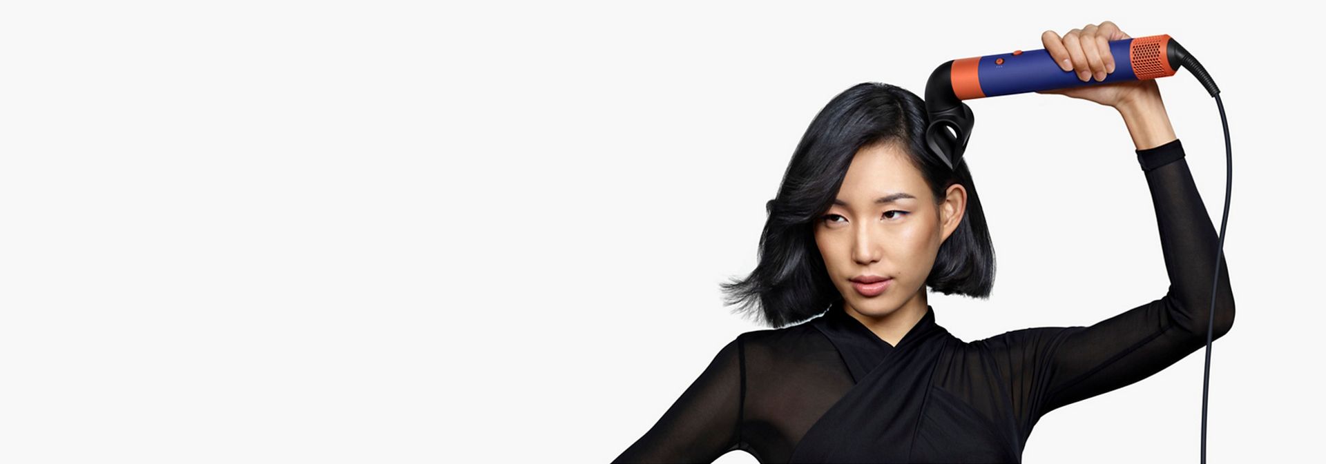 En model med mellemlangt sort hår bruger Blade Concentrator til at style håret.