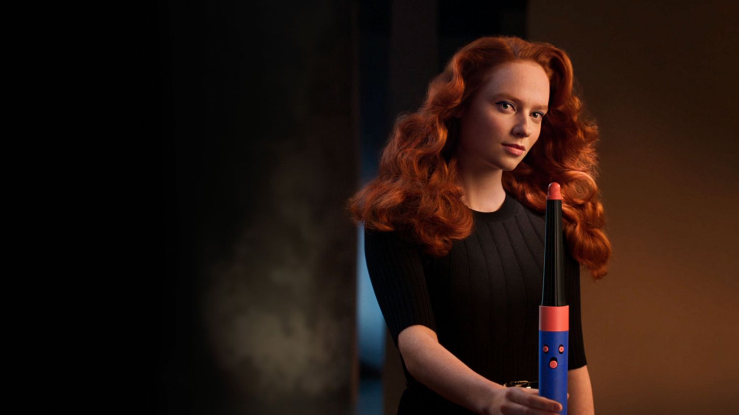 Frontalansicht einer Frau mit lockigem, gestyltem Haar, die den Dyson Airwrap ID hält.