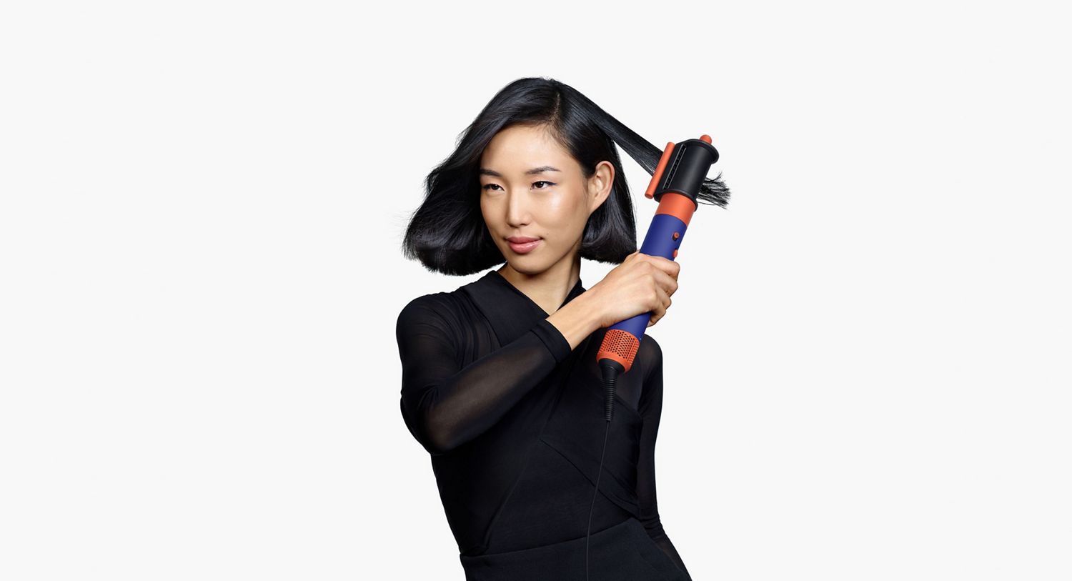 Model using the Dyson Airwrap i.d. to style hair.