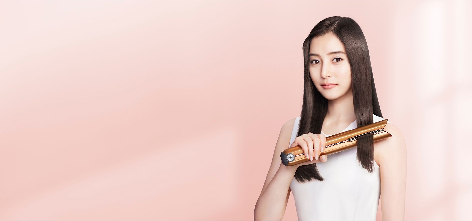 Dyson Corraleヘアアイロン コッパー/ブライトニッケルで、髪をストレートにする女性
