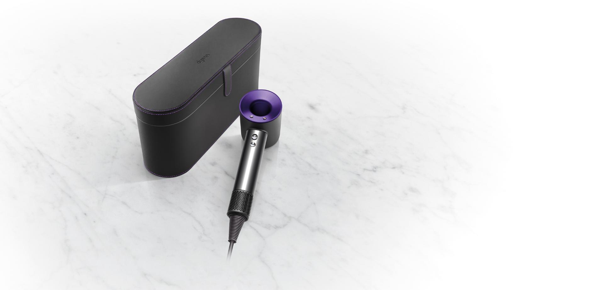 czarne etui i leżąca obok suszarka Dyson Supersonic w kolorze czerń/fiolet