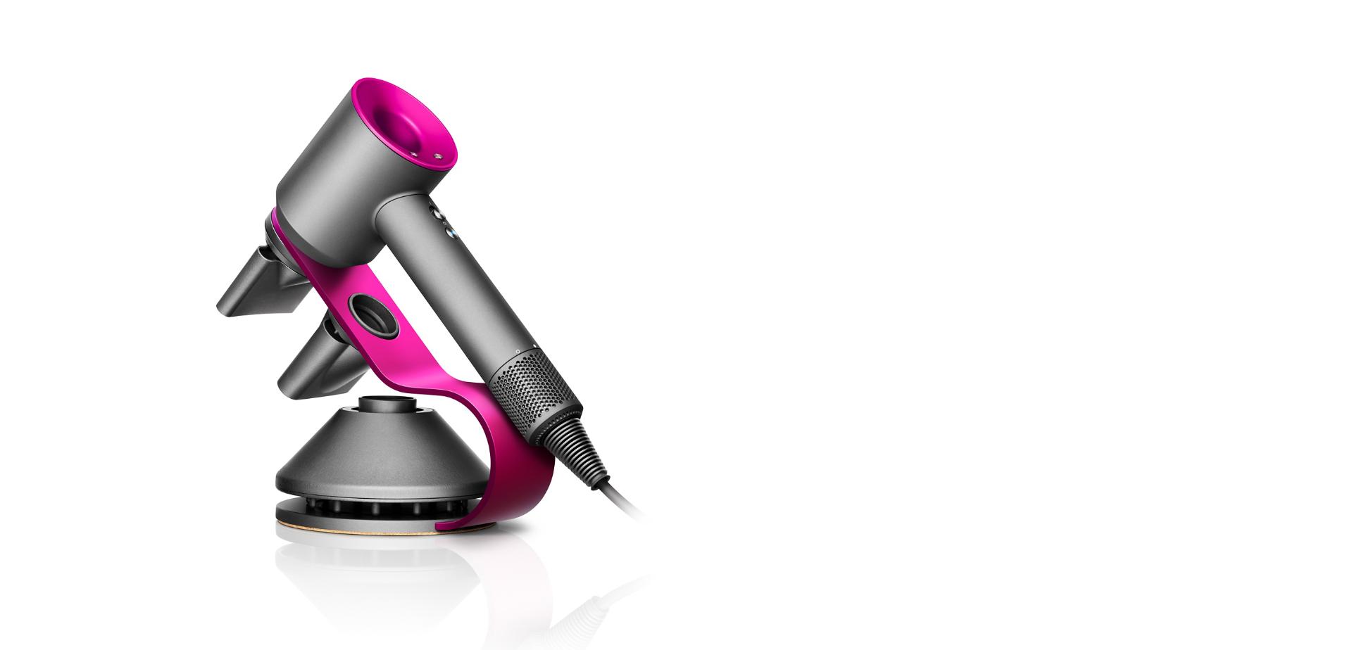 Suszarka Dyson Supersonic w kolorze Stali i Fuksji leży oparta na stojaku
