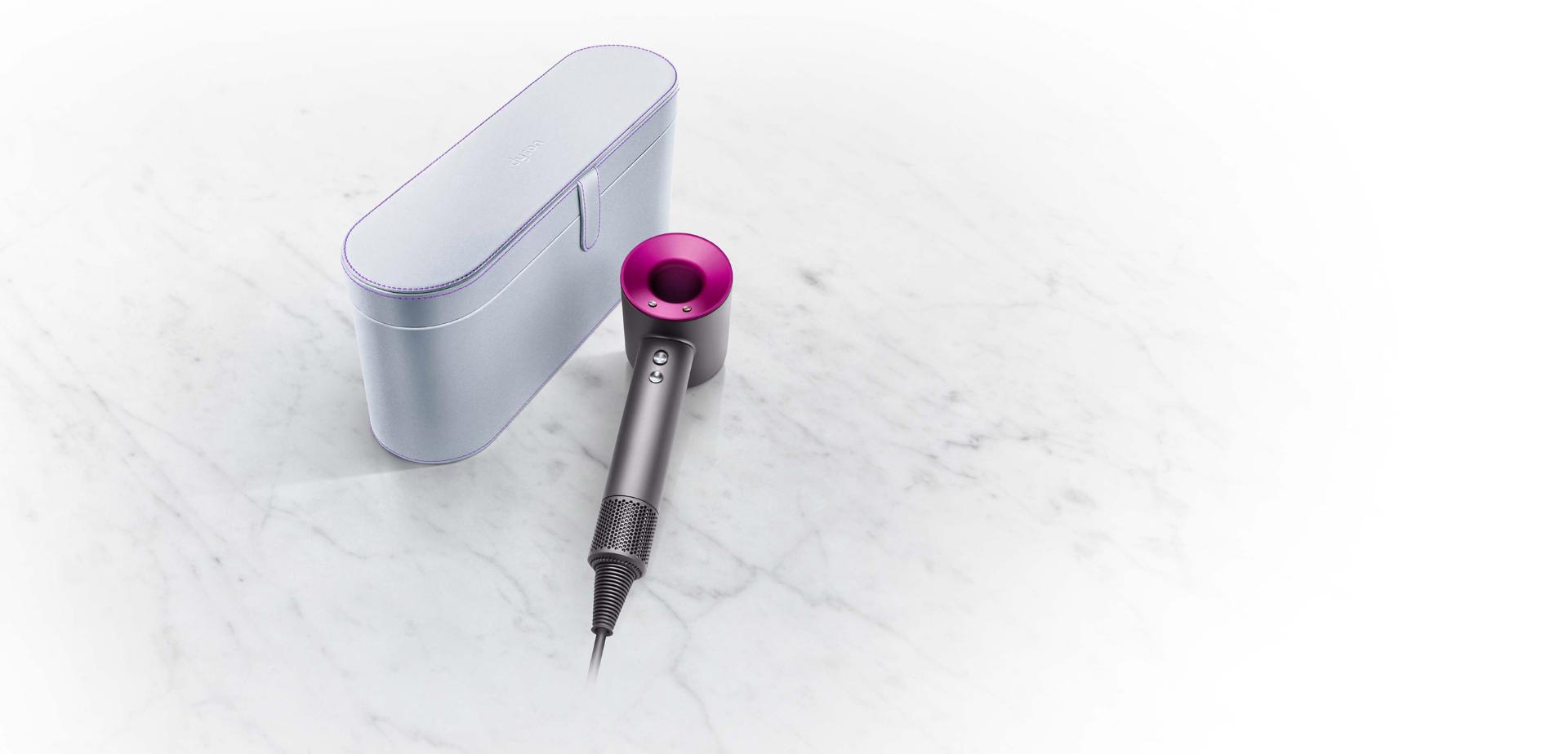 srebrne etui i leżąca obok suszarka Dyson Supersonic w kolorze stal/fuksja