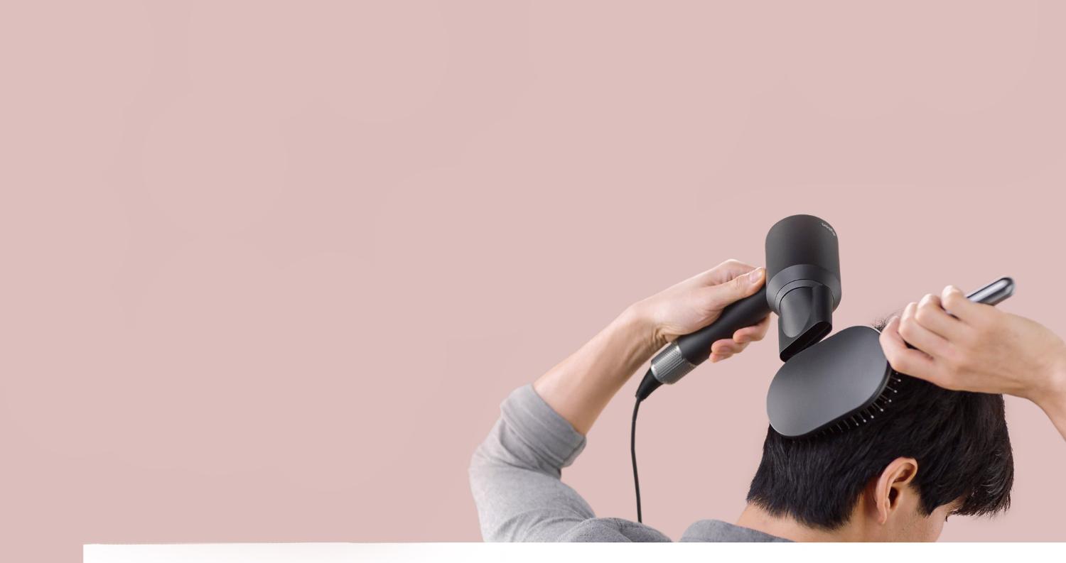 Model met haartype 1 borstelt zijn natte haar met de Dysonborstel en droogt zijn haar met de Dyson Supersonic haardroger
