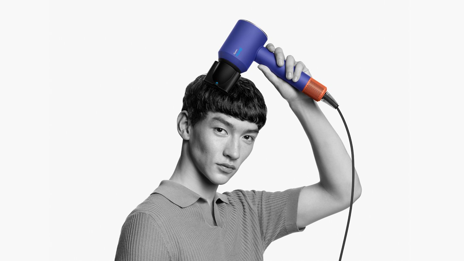 A model with a short textured crop uses the Smoothing nozzle to simultaneously style and dry his hair.