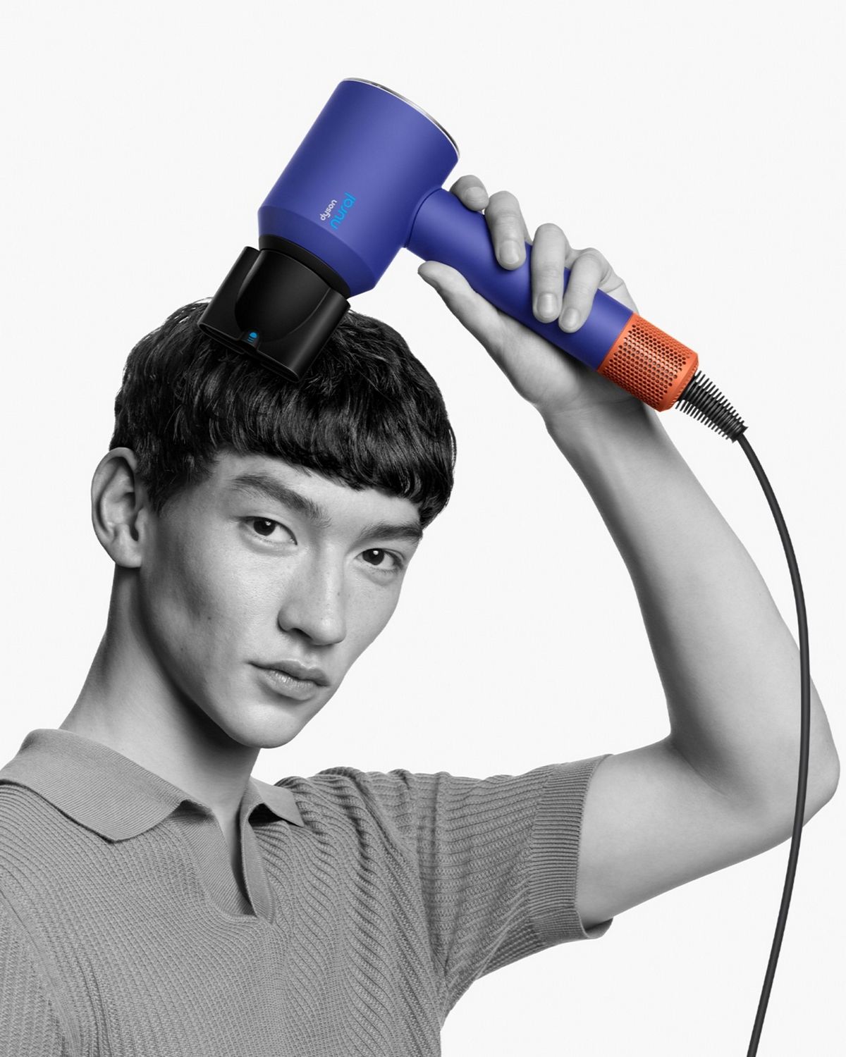 A model with a short textured crop uses the Smoothing nozzle to simultaneously style and dry his hair.