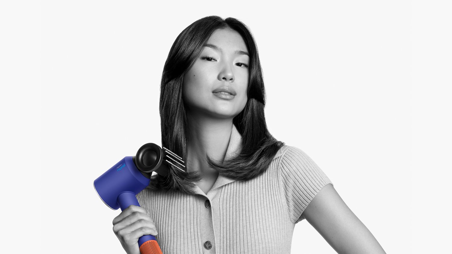 A model with straight hair uses the Flyaway attachment on the Dyson Supersonic Nural hair dryer to smooth her hair.