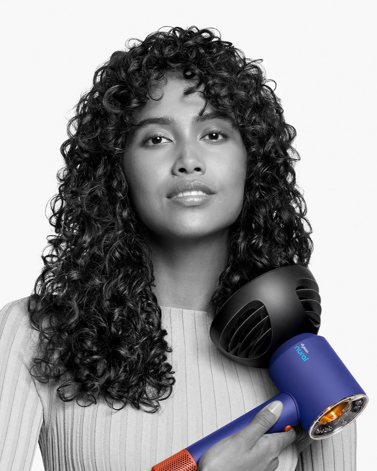 A model with straight hair uses the Flyaway attachment on the Dyson Supersonic Nural hair dryer to smooth her hair.