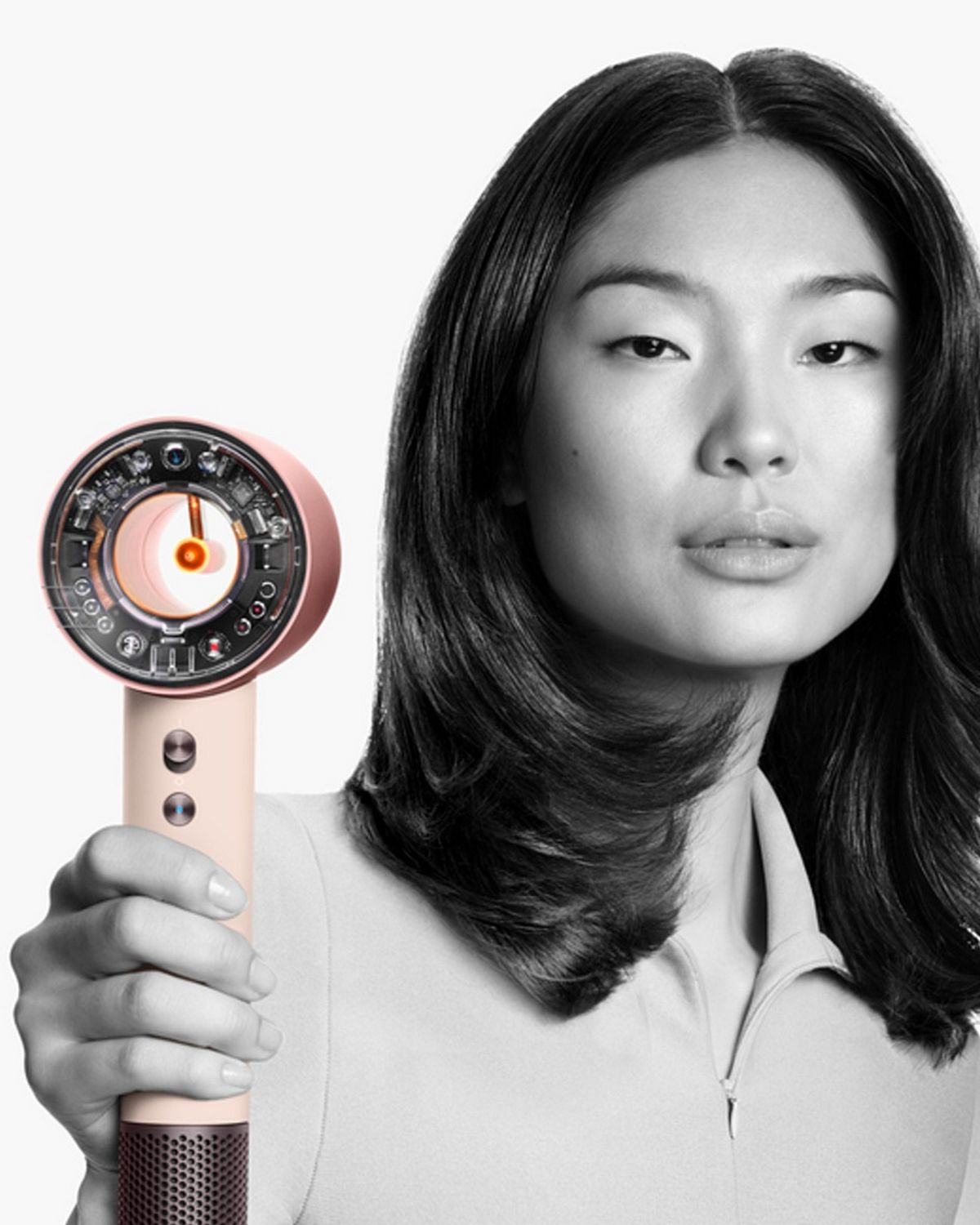 A model with straight, shoulder-length hair holds out the Dyson Supersonic Nural hair dryer.