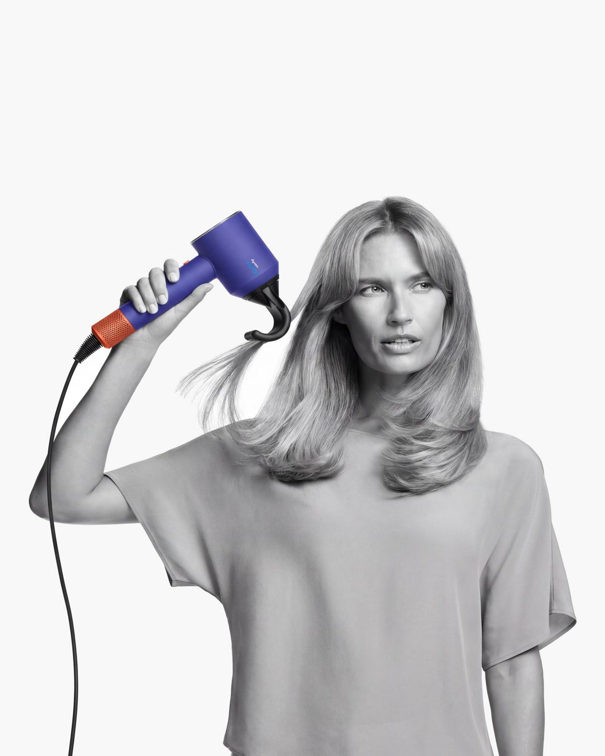 A model with straight hair uses the Flyaway attachment on the Dyson Supersonic Nural hair dryer to smooth her hair.