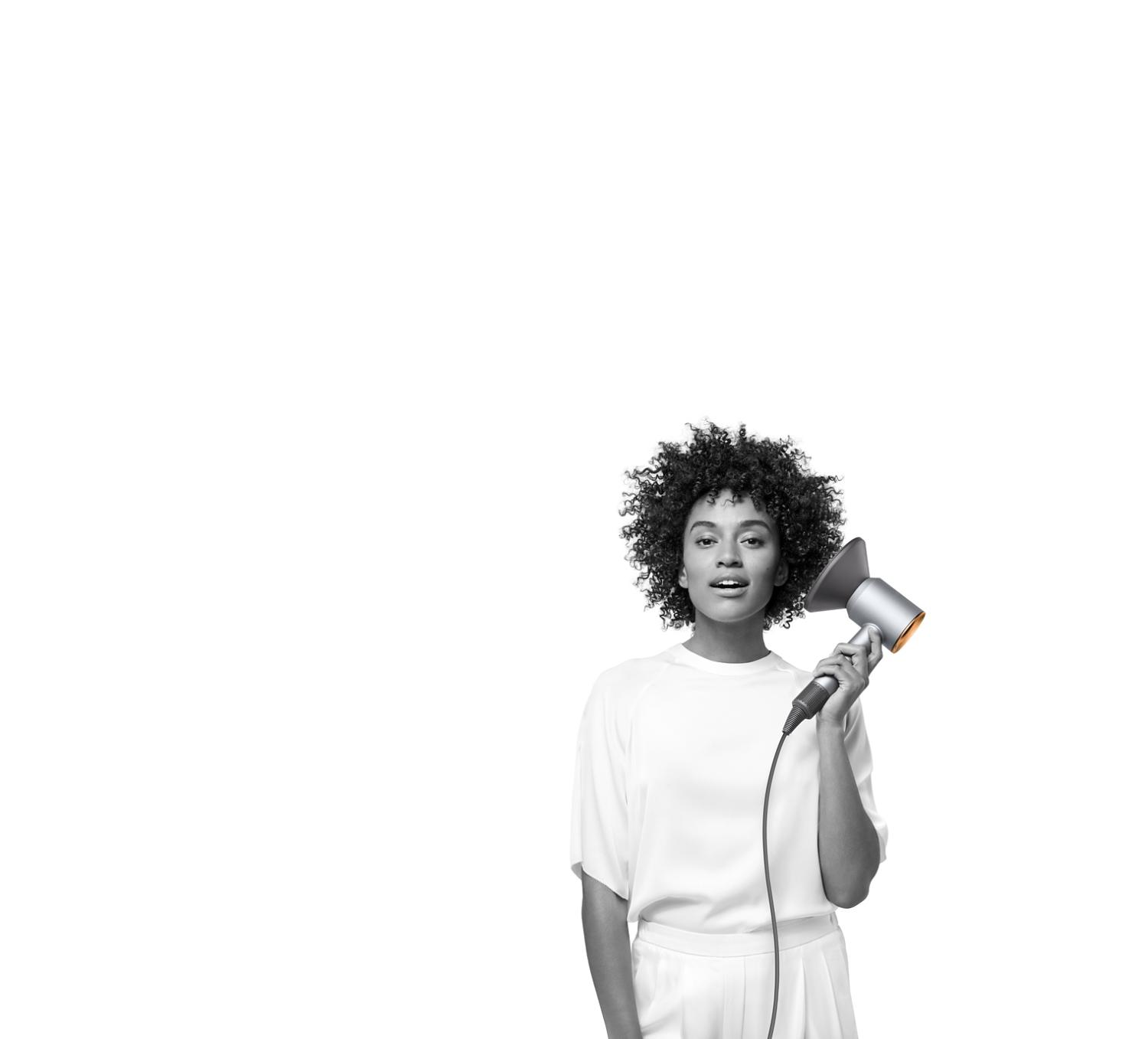 Woman dries hair with copper Dyson Supersonic hair dryer