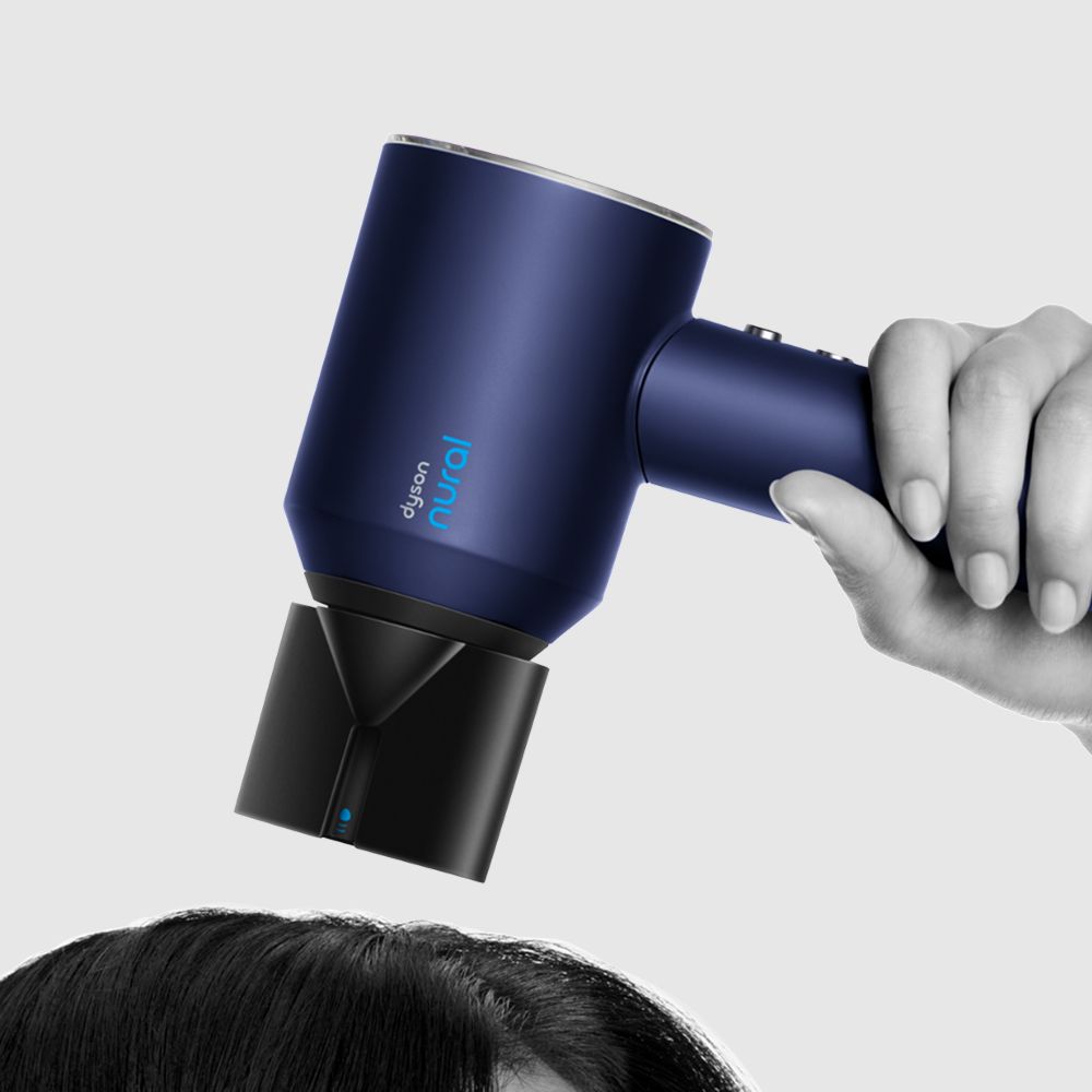 A model styles her hair with the Dyson Supersonic Nural hair dryer and Wave+Curl diffuser.