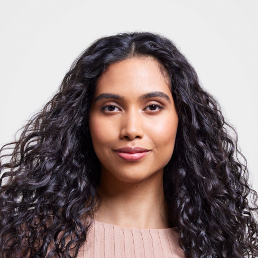 Model with long dark hair styled with the Dyson Supersonic Nural hair dryer.