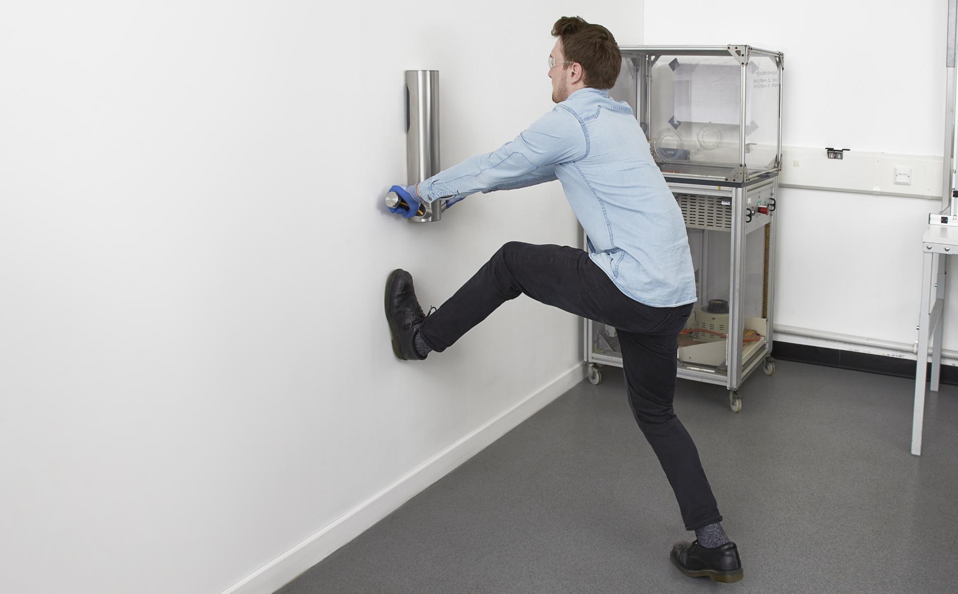 Engineer testing robustness of Dyson Airblade 9kJ hand dryer