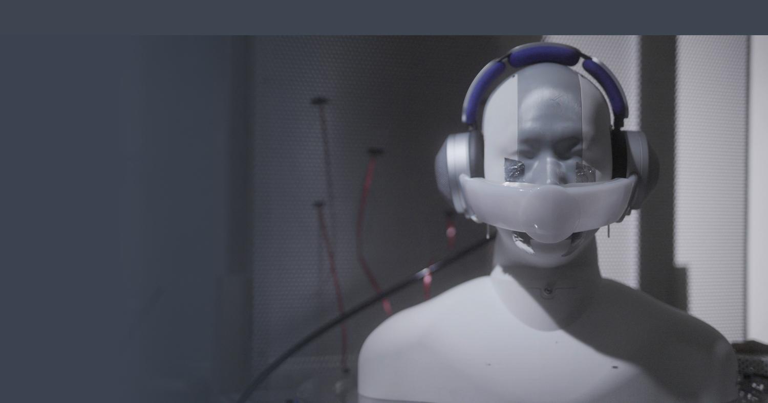 Manikin wearing prototype headphones, with visor across nose and mouth