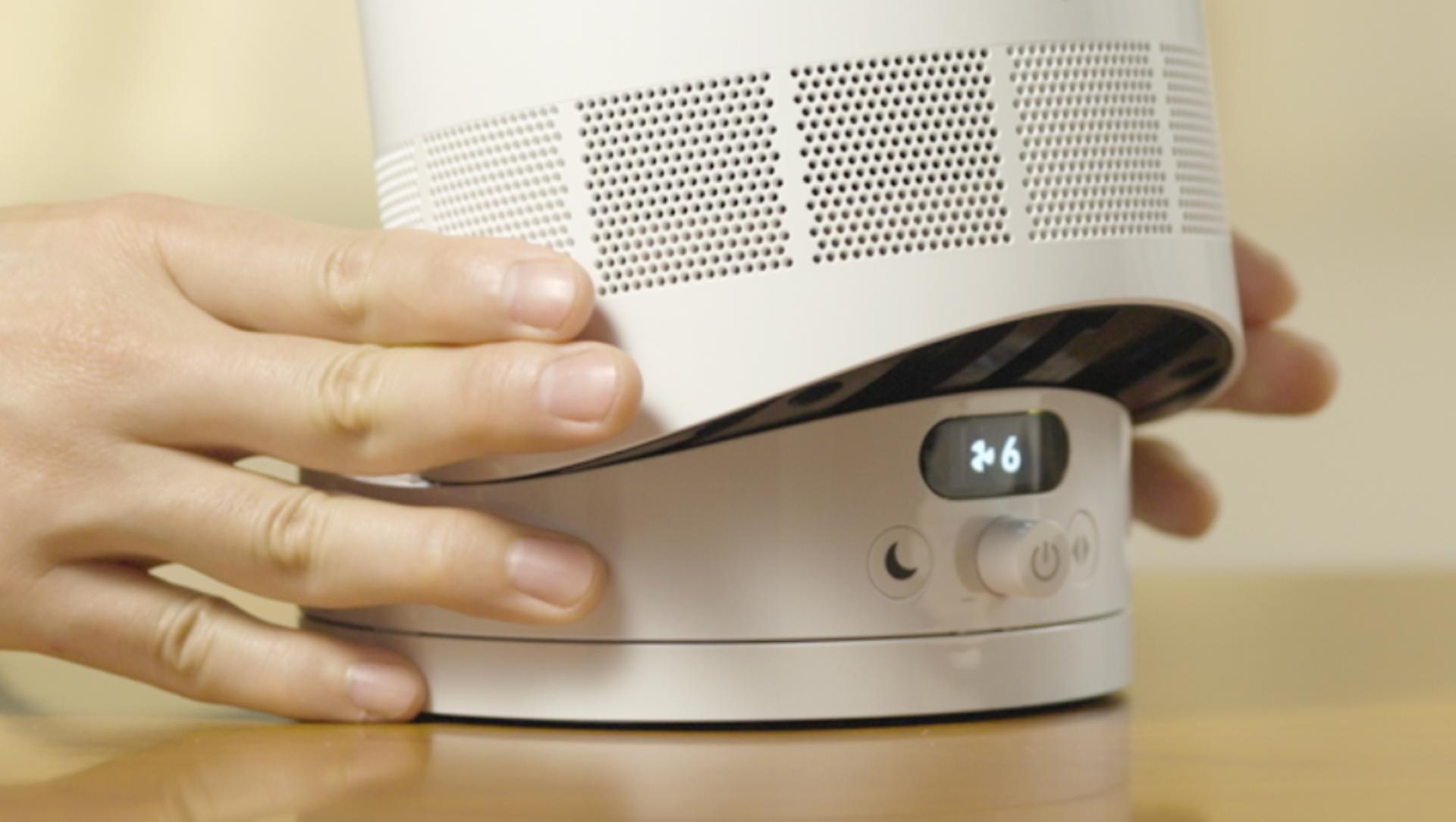 A person tilts the Dyson Cool CF1 fan on its base to direct the airflow.