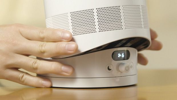 A person tilts the Dyson Cool CF1 fan on its base to direct the airflow.