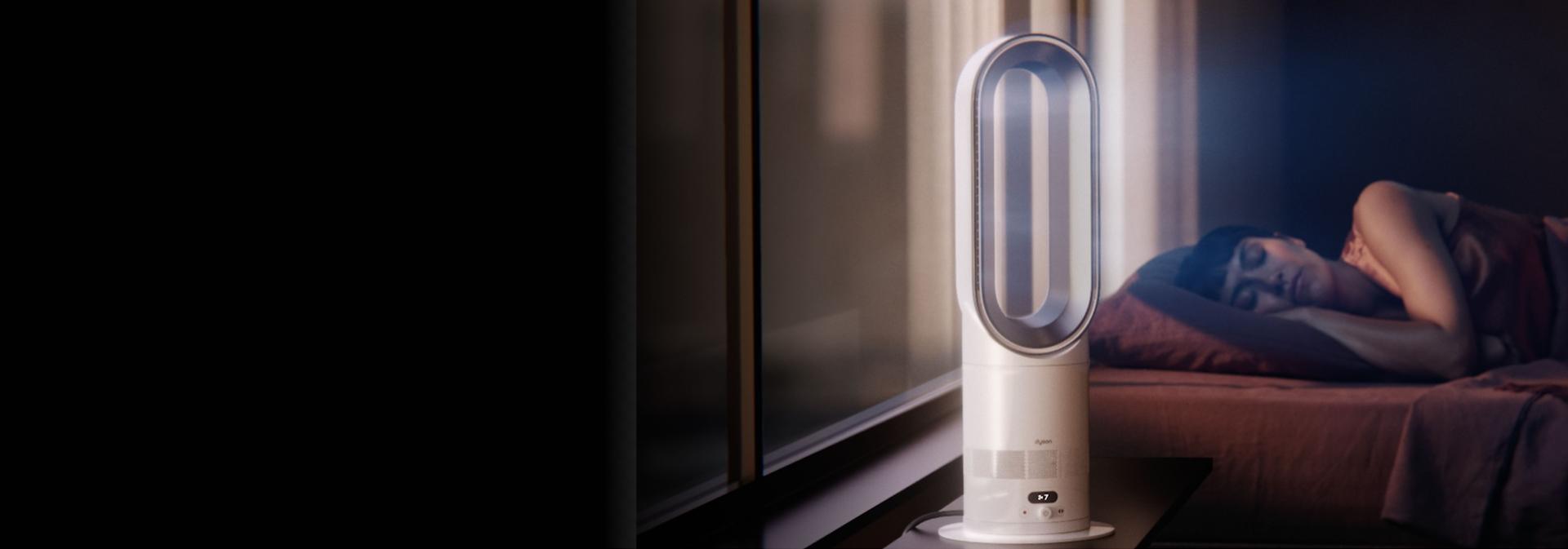 The Dyson Hot+Cool HF1 Remote Link Pre-heat heater and cooling fan operates quietly in a bedroom near a sleeping person.