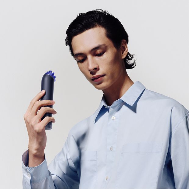 The Dyson HushJet Mini Cool portable fan held upright in a hand.