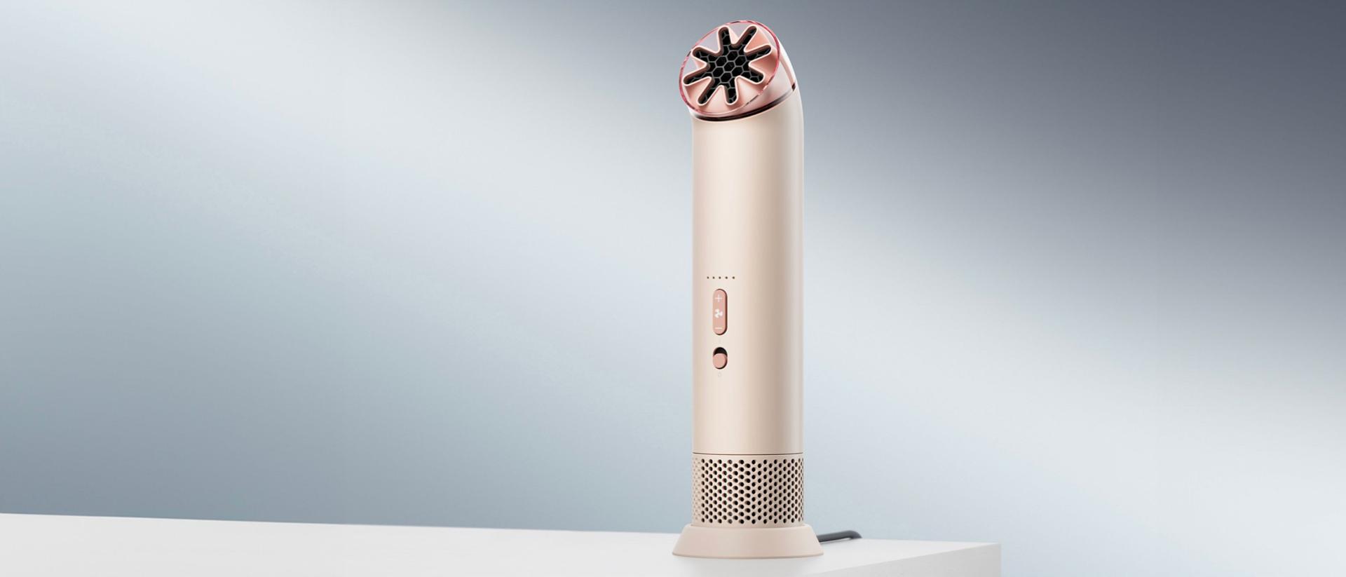 Prijenosni ventilator Dyson HushJet Mini Cool na stalku za punjenje na stolu.