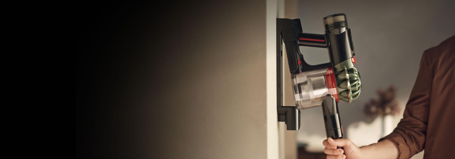 The Dyson V8 Cyclone vacuum is returned to its charging dock.