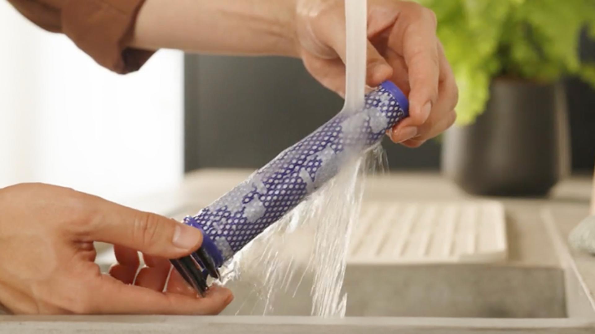The Post-motor filter is rinsed under running water from a tap.