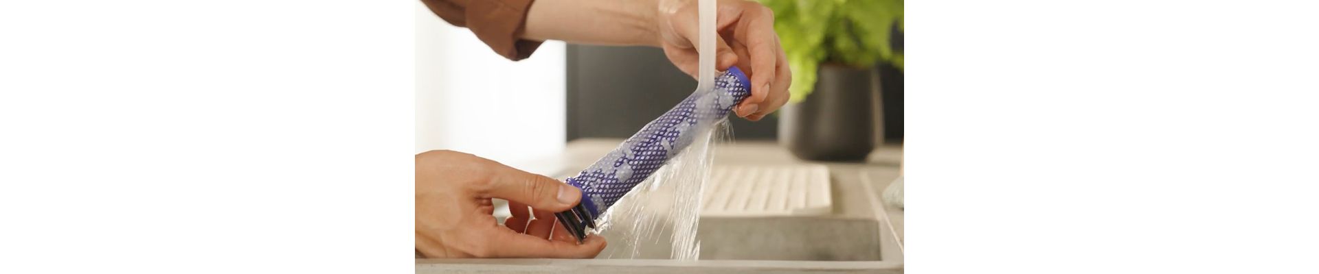 The Post-motor filter is rinsed under running water from a tap.