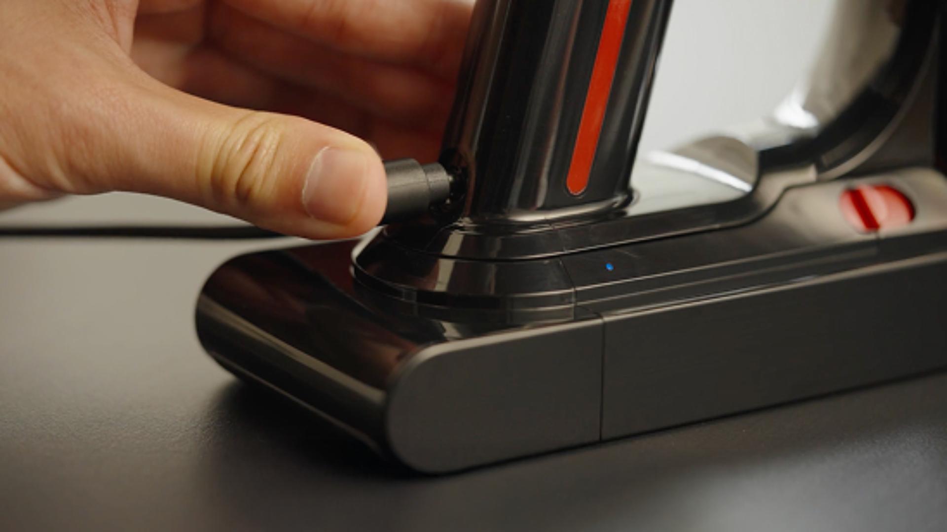 The battery of the Dyson V8 Cyclone vacuum is plugged into charge.