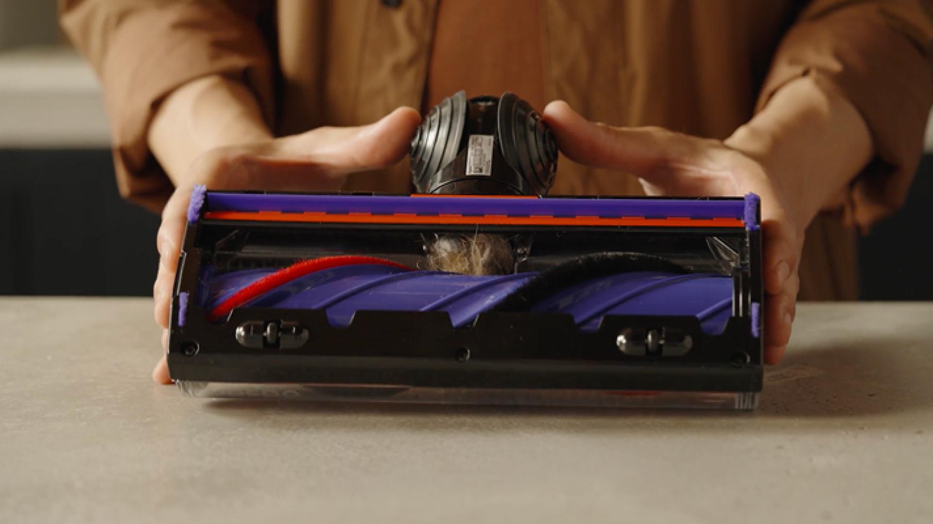A Dyson owner checks the neck of their cleaner head for blockages.