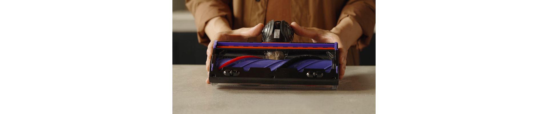 A Dyson owner checks the neck of their cleaner head for blockages.
