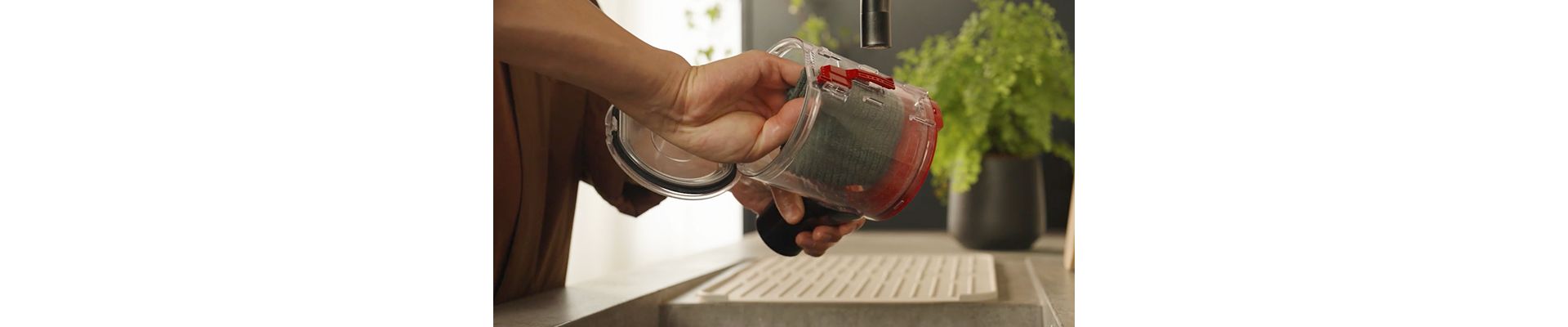 The clear bin of the Dyson V8 Cyclone vacuum is wiped clean with a damp cloth.