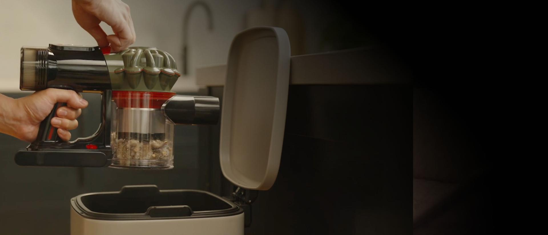 يتم تفريغ المكنسة الكهربائية اللاسلكية Dyson V8 Cyclone في سلة المهملات المنزلية.