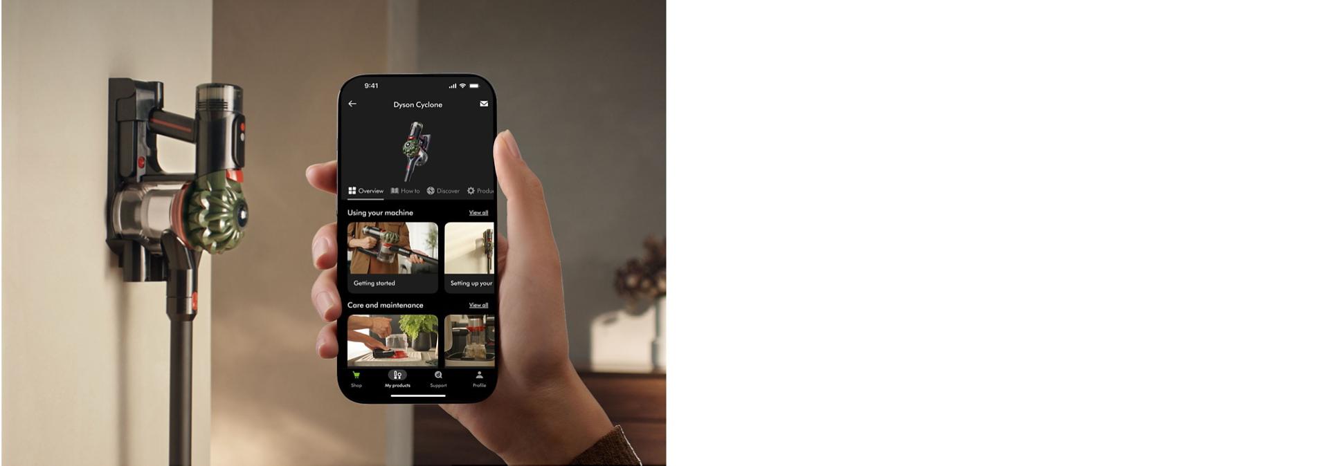 مكنسة Dyson V8 Cyclone اللاسلكية على قاعدة الحائط الخاصة بها مع هاتف يعرض تطبيق MyDyson.