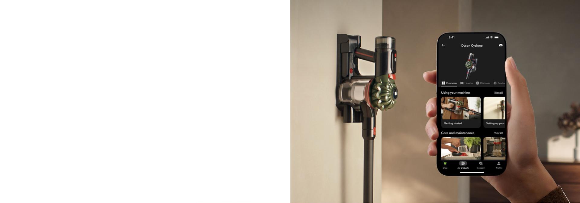 The Dyson V8 Cyclone cordless vacuum on its wall dock with a phone showing the MyDyson app.
